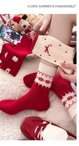 Detailaufnahme dicker Strick-Weihnachtssocken mit Schneeflocken und roten Schleifen