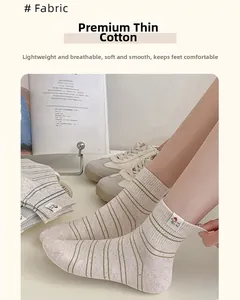 Gros plan de chaussettes fines en coton beige avec rayures vertes et étiquette de chiot