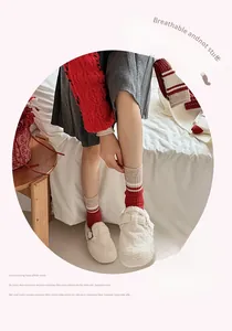 Detail of red and white striped cashmere socks paired with plush mule slippers