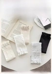 Close-up of silk mesh heart patterned socks with ruffle cuffs in four neutral colors