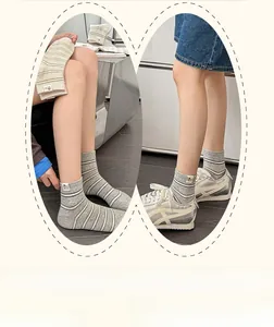 Détail de chaussettes grises rayées avec écusson cartoon et style basket de sport