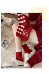Detail der roten und weißen Wollsocken mit weihnachtlichen Rentier- und Schneeflockenmotiven