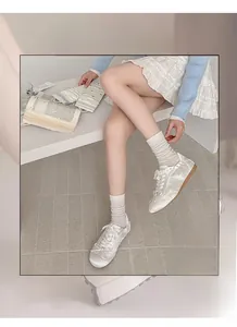 Detailed shot of white vertical striped crew socks paired with white sneakers and skirt