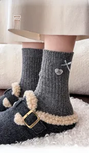 Detail of wool socks with blue ribbon bows and metal heart pendant in cozy shoes