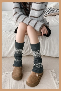 Detailed close-up of dark grey Fair Isle knit leg warmers with vintage white patterns
