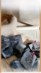 Detail of grey diamond-knit socks with dog embroidery and tricolor ribbon detail