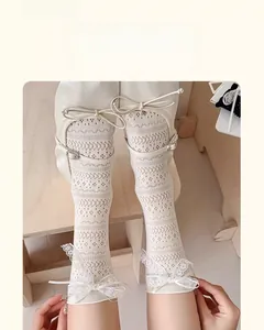 Detail of white lace calf socks featuring mesh texture and silk bow with rhinestone buckle