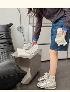 Détail de chaussettes rayées en coton crème avec broderie cœur sur un fauteuil