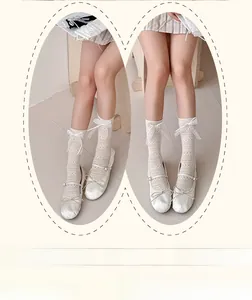 Close-up of white lace calf socks with side ribbon bows and delicate mesh hollow patterns