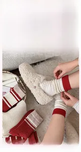 Detail of warm lamb wool slippers paired with red striped knit cashmere socks for winter