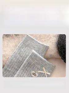 Detail of light blue wool socks with a white silk bow and heart-shaped silver charm