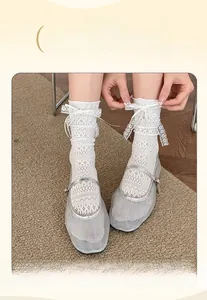 Detail view of white lace crew socks with bow ribbons and mesh pattern for women