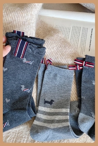 Close-up of grey mid-calf socks with dachshund embroidery and tri-color ribbon detail