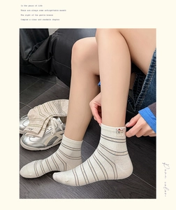 Gros plan de chaussettes en coton rayées crème avec un patch brodé chien mignon