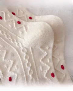 Nahaufnahme der verstärkten Ferse und Zehen beige gestrickter Wollsocken mit roten Punkten