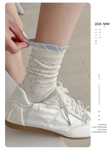 Detail of white crew sock with blue polka dots and ruffle trim paired with sneakers