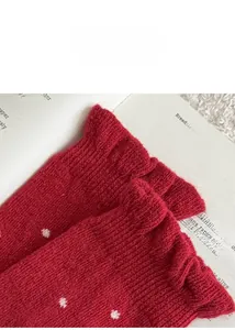 Detailaufnahme der roten, dicken Wollsocken mit weißen Punkten und Rüschendetails am Saum