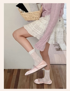 Detail of pink silk crew socks with heart patterns paired with ballet flats and lace skirt