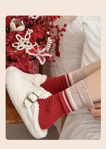 Detail of red and white striped cashmere knit socks with plush cream mule slippers