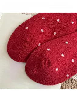 Detail von roten Wollsocken mit weißer Rautenstickerei und warmer Strickstruktur