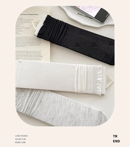 Detail of heart pattern mesh socks with ruffled cuffs in black, white and grey colors