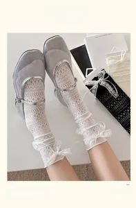 Detail of white lace mesh socks with ribbon bows paired with silver Mary Jane shoes