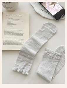 Close-up of light grey silk crew socks with floral texture and ruffled edge trim