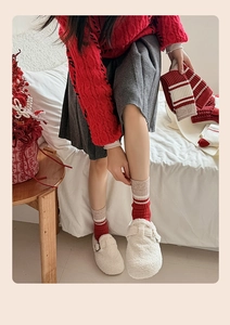 Close-up of red and beige striped cashmere knit socks with cozy white fleece buckle mules
