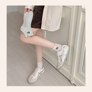 Close-up of cute cartoon cat embroidery on ribbed ankle socks with casual sneakers