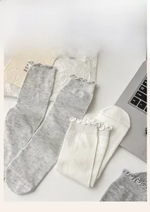 Detail view of ballet style ruffle trim knit socks in grey and white soft silk fabric