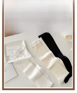 Detail of ribbed cuffs on silk knee-high socks in white, beige, and black colors