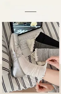 Detail of ballet style ruffle trim socks paired with silver Mary Jane shoes on a bed
