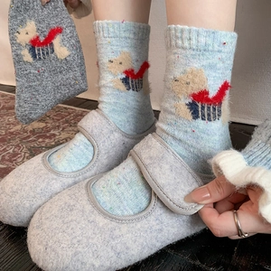 Thick wool socks with cartoon dog motif paired with grey Mary Jane slippers on rug