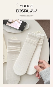 Détail de chaussettes blanc crème avec bordure à volants et texture côtelée sur table