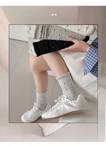 Close-up of mesh polka dot socks with ruffled edges in gray, black, and beige colors