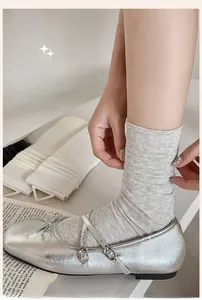 Detail of breathable grey cotton mid-calf socks styled with silver Mary Jane shoes