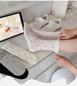Close-up of white, grey, and black polka dot mesh crew socks with ribbed texture