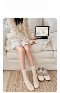 Detail view of cream hollow-out knit knee-high socks for women in soft home setting