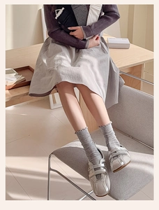 Light gray ruffle trim crew socks paired with vintage sneakers in a cozy home setting
