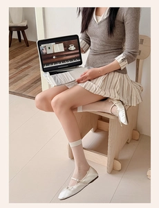 Detail of sheer glass silk socks paired with white bow ballet flats in a cozy setting