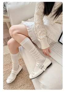 Top view of white silk calf socks paired with double buckle Mary Jane shoes and a bow