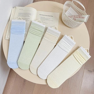 Set of five hollow bow mesh socks in pastel colors neatly displayed on a cream table