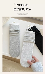 Close-up of gray and black cotton crew socks with ribbed cuffs and packaging tags