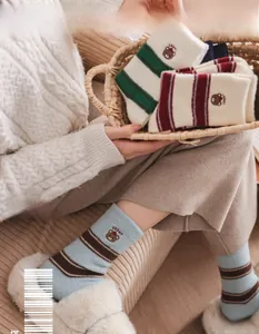 Detail of striped socks with bear embroidery in light blue, green and red colors