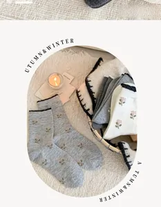 Detail of cashmere socks with floral patterns and black wavy edges on a cozy rug