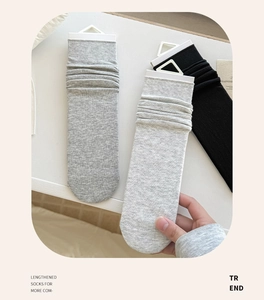 Close-up of lengthened knit socks in dark grey, light grey, and black colors
