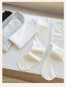Close-up of neutral cotton crew socks in black, grey, and off-white with ribbed cuffs