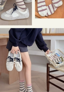 Close-up of cream striped crew socks paired with off-white leather casual sneakers