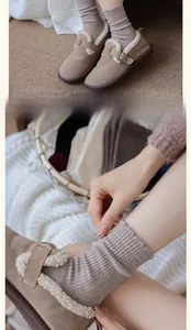 Close-up of tan suede mule slippers with warm shearling lining and metal buckle detail