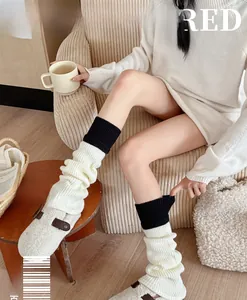 Detail of black and white color-block knit leg warmers paired with white plush mules